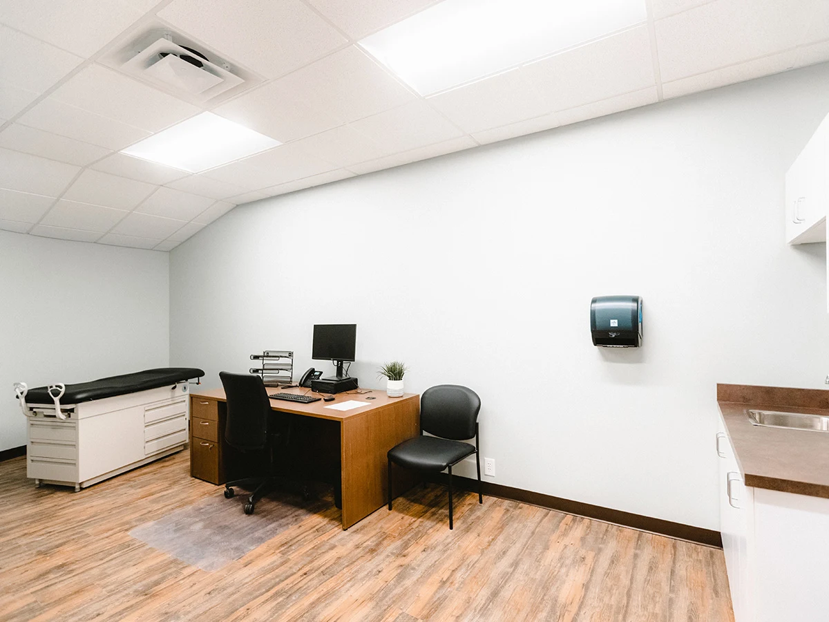 Clinical assessment room with desk and exam table