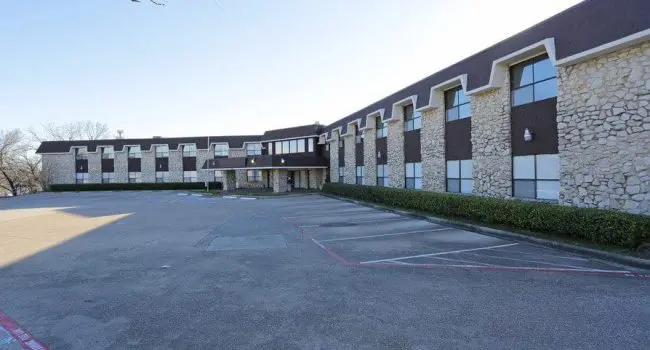 Exterior view of Homeward Bound Inc. Dallas Residential Treatment Center with a stone facade and empty parking lot in front