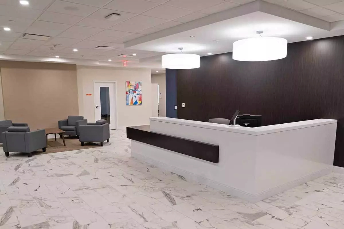 Modern reception desk with gray seating and white tile floor