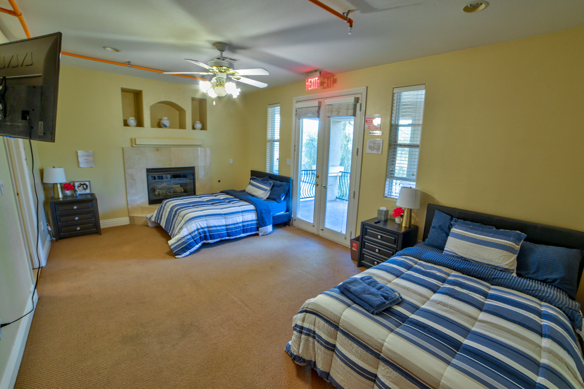 Shared bedroom with two beds, a fireplace, and a balcony.