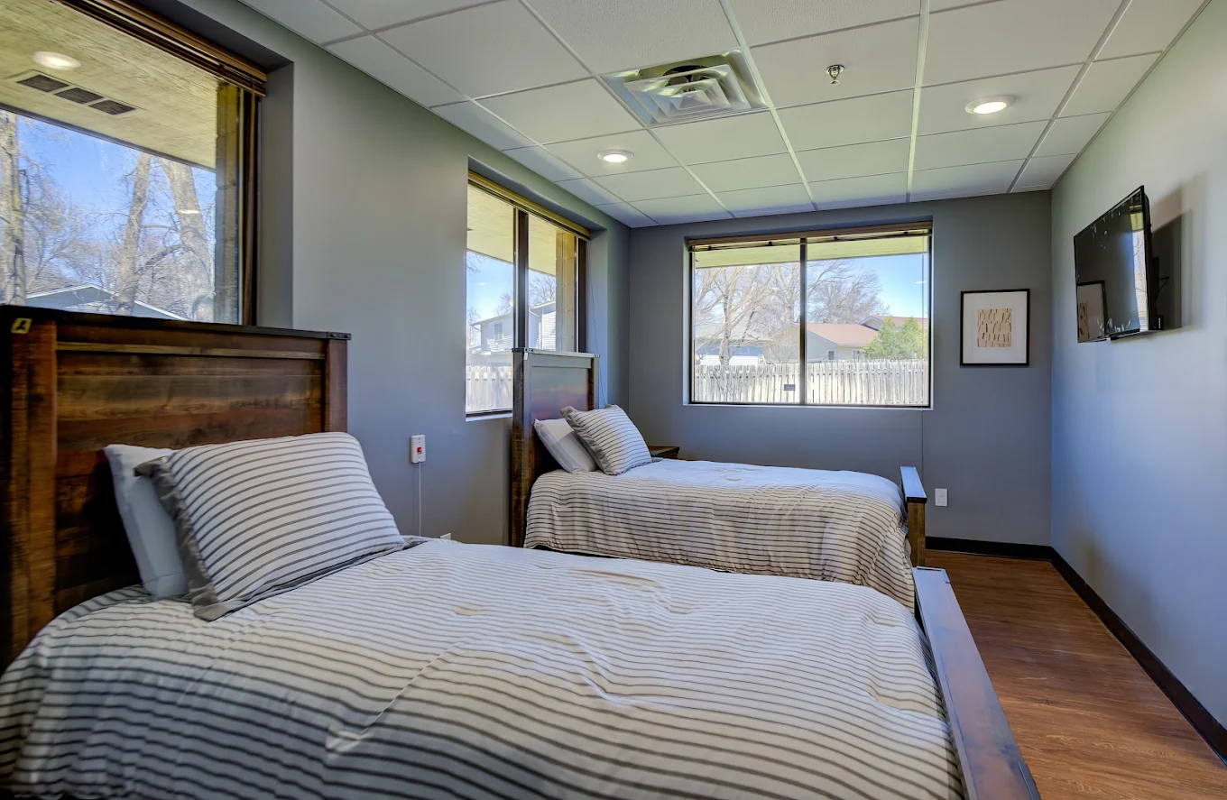 Two twin beds in shared room with large windows