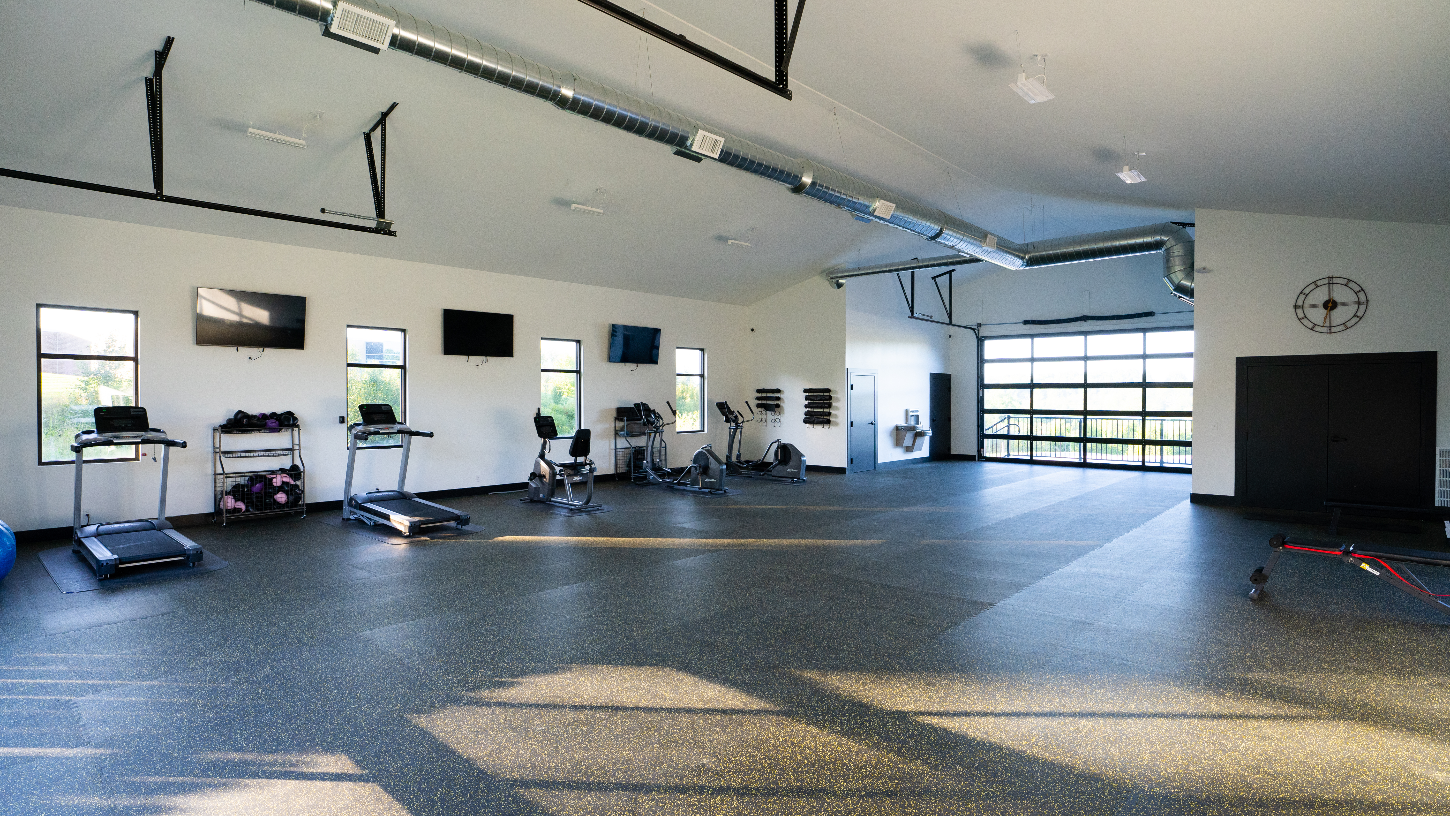 Spacious gym with treadmills, bikes, and large windows