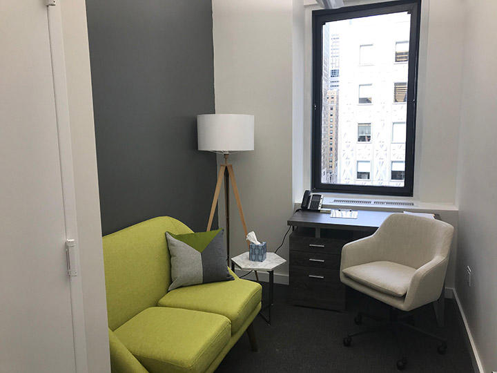 Therapy room with green sofa and desk.