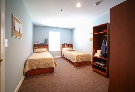 Two twin beds with wood furniture and a single window