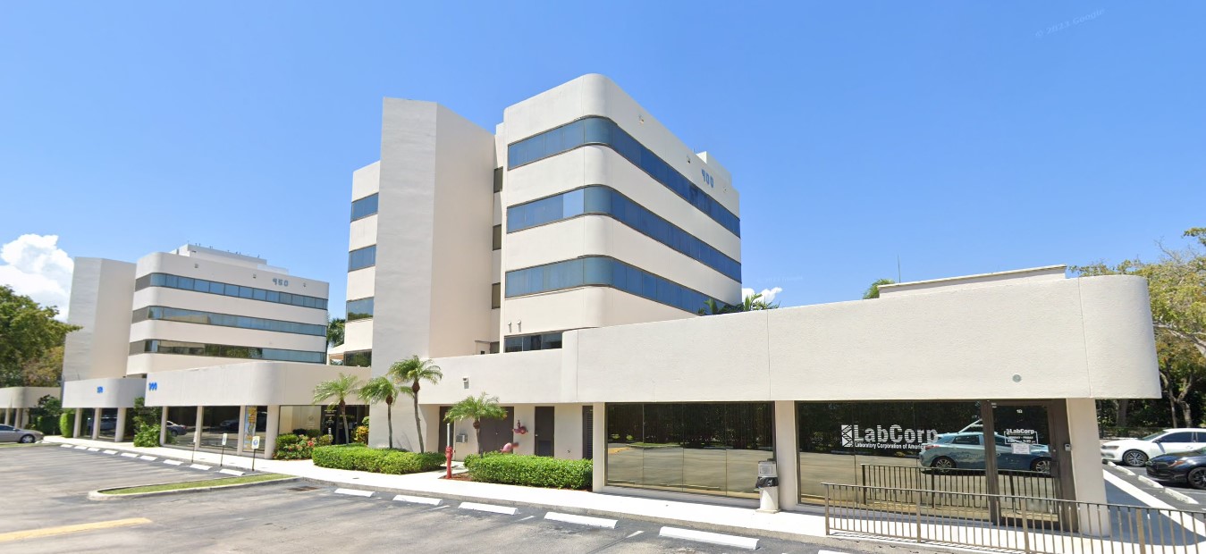 White multi-story building with glass windows and palm trees