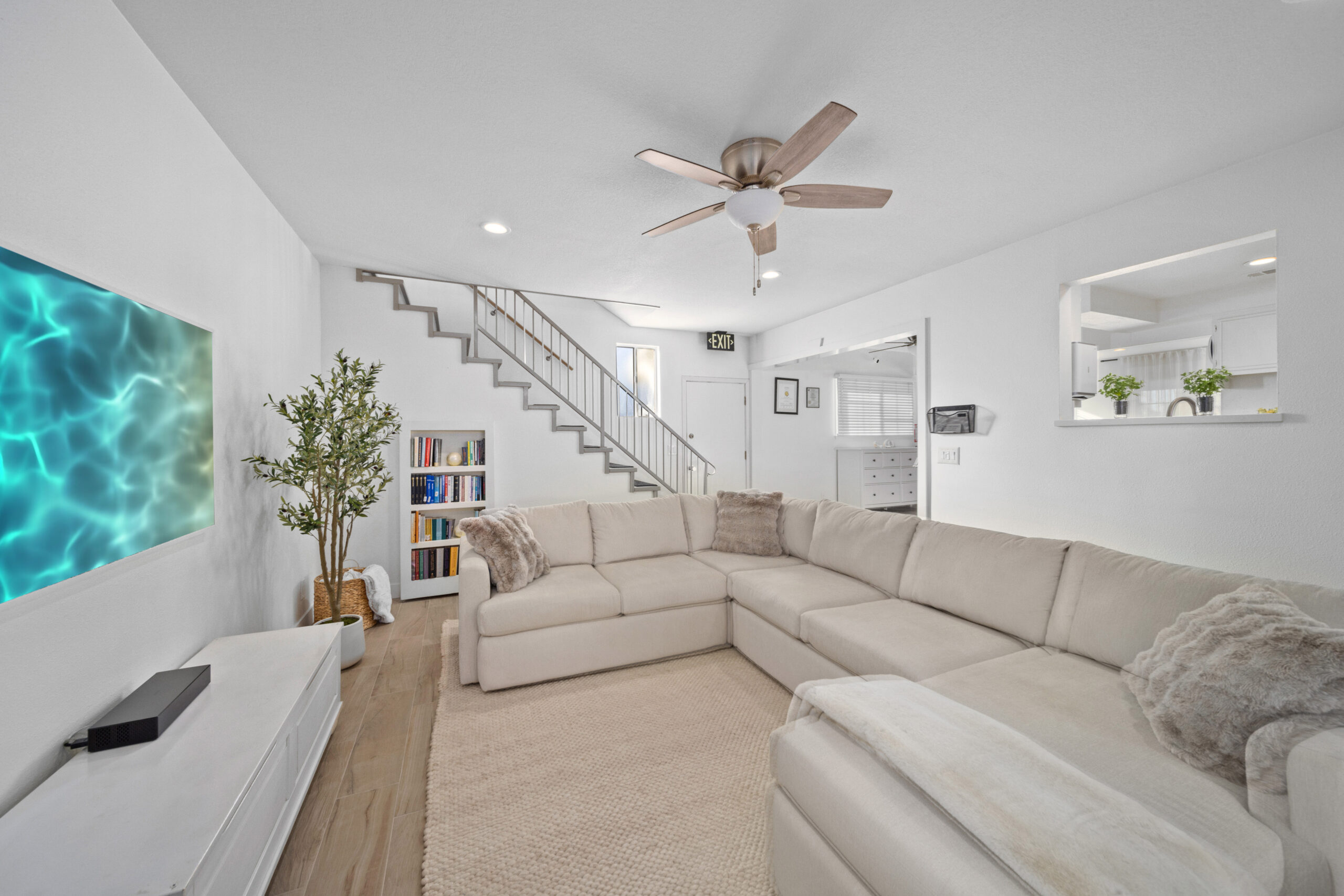 White sectional couch with bookshelf and staircase view