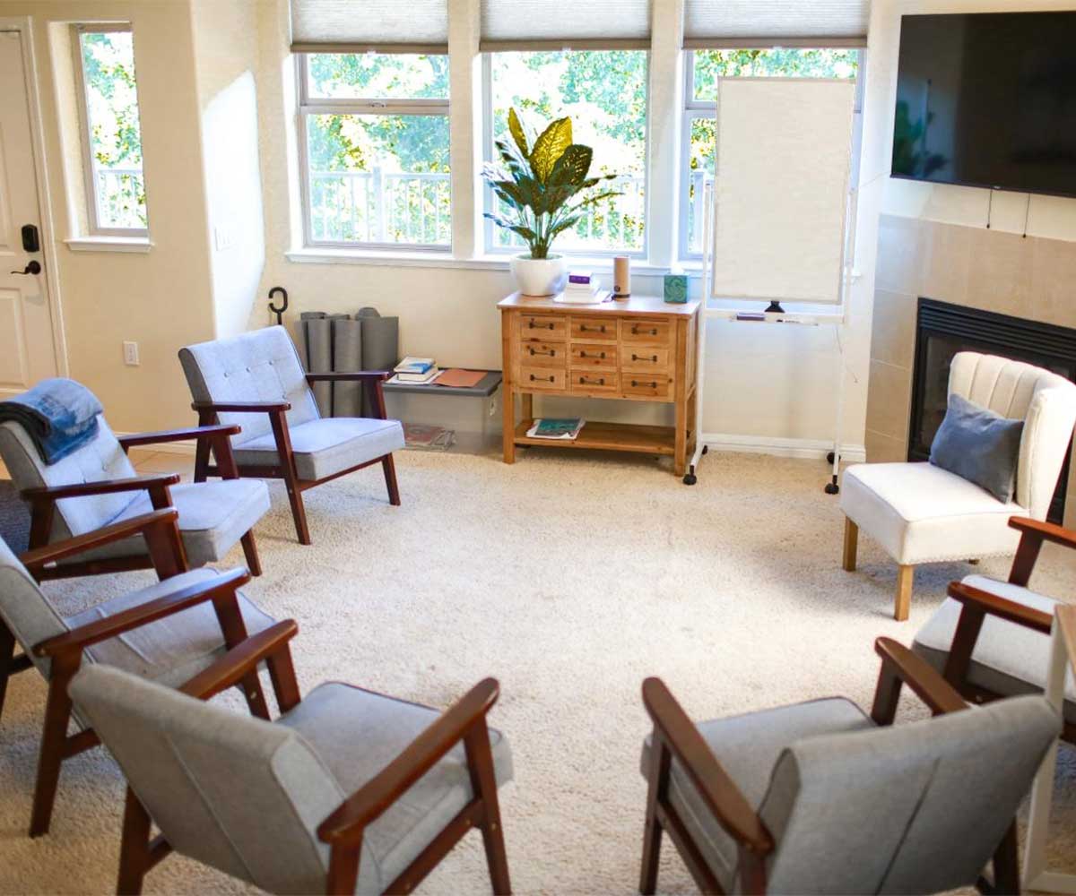 Therapy circle with armchairs and fireplace in bright room