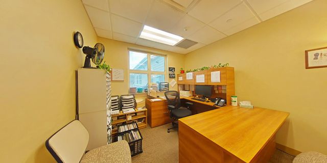 Small office with wood desk, files, and window