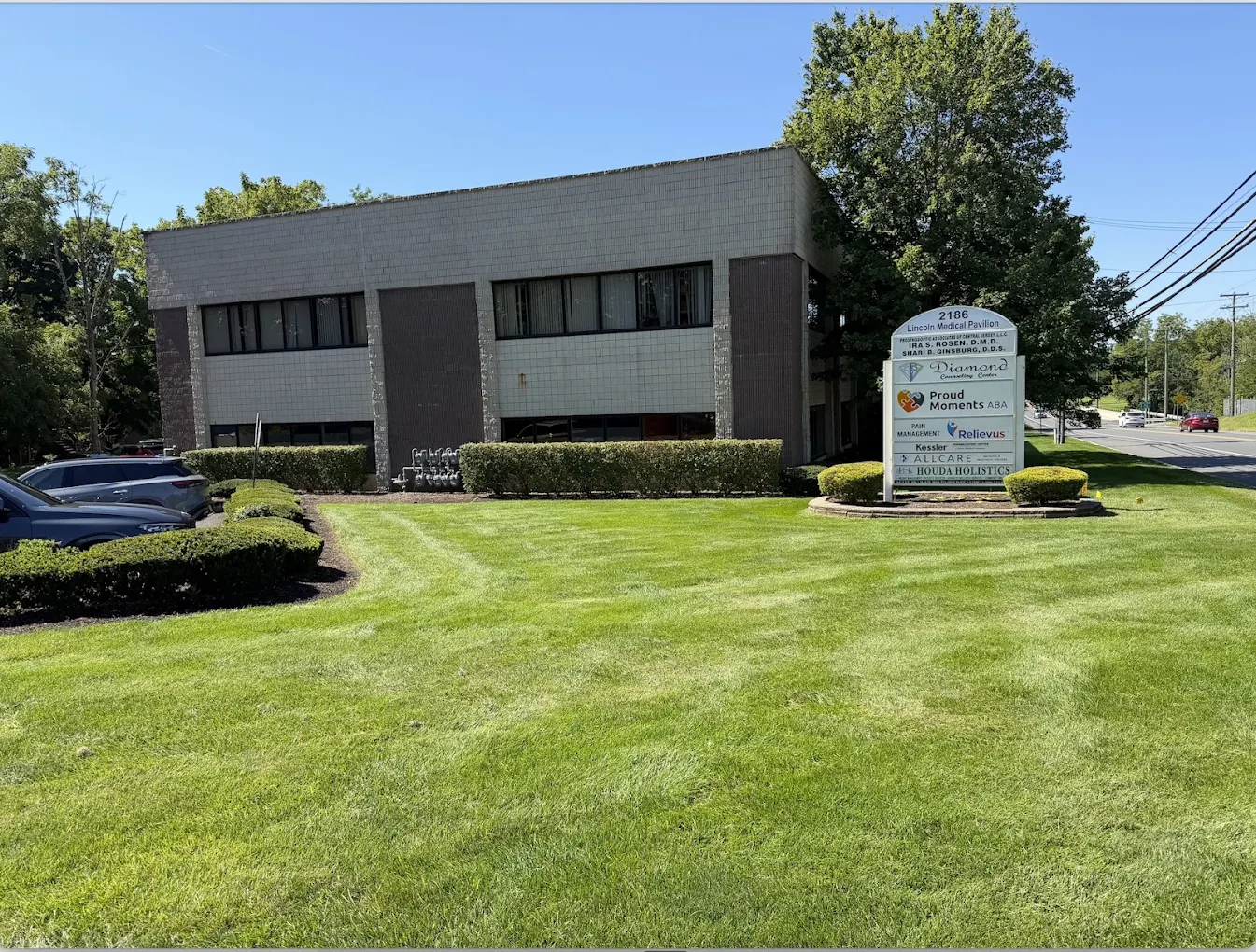 Two-story gray office building with lawn and trees
