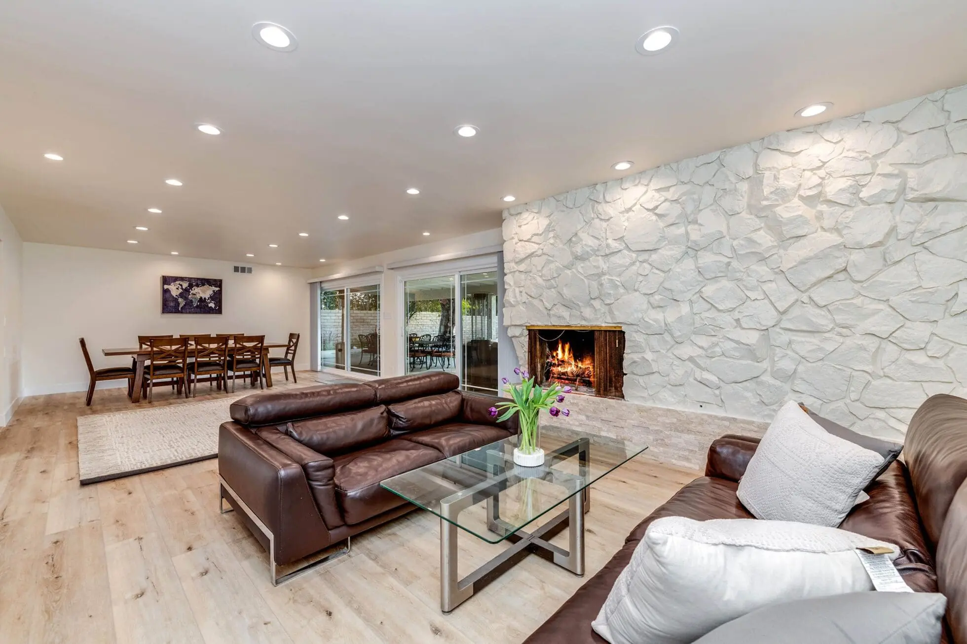 Leather sofas facing a stone fireplace and glass table
