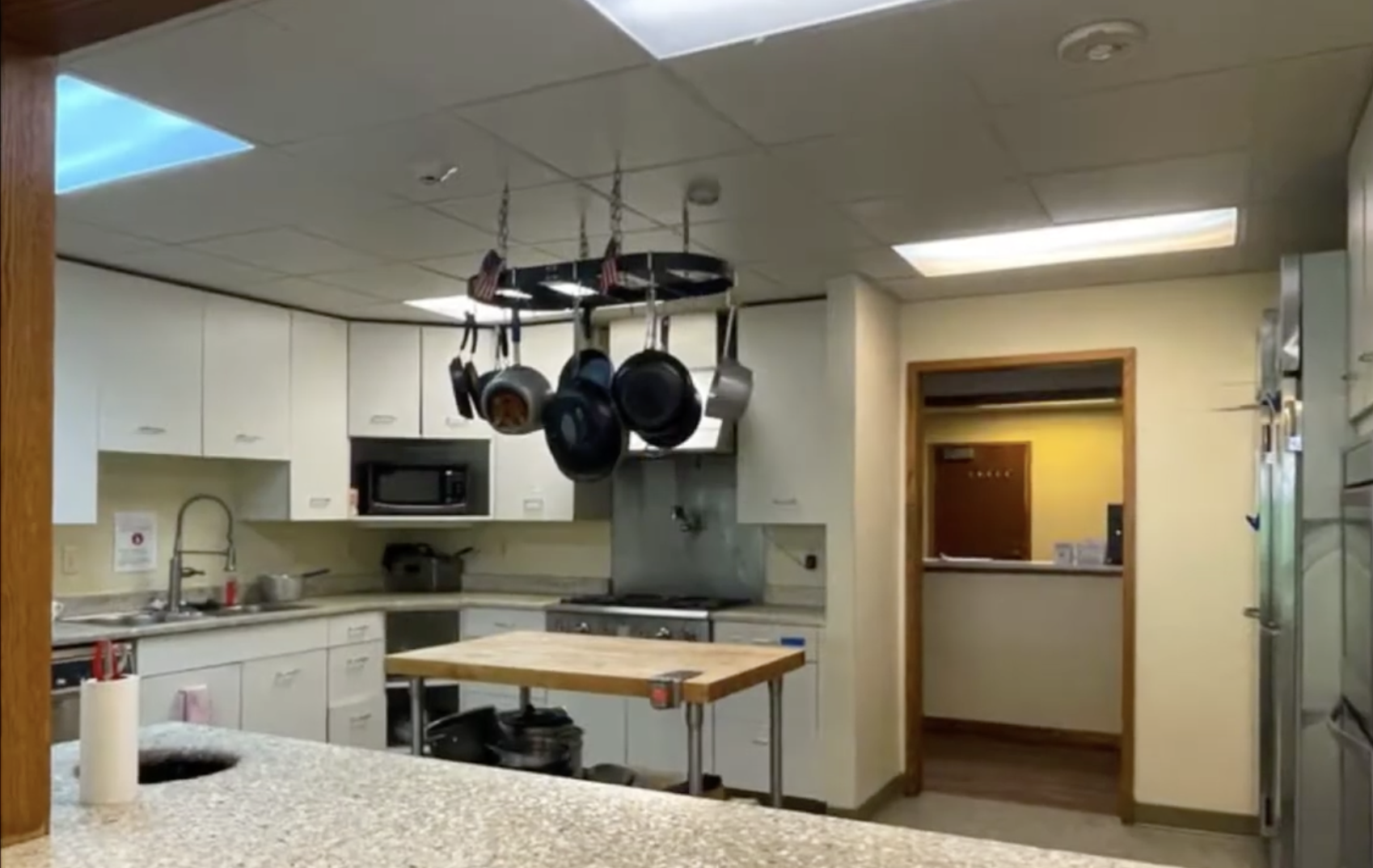 Shared kitchen with white cabinets and hanging pots
