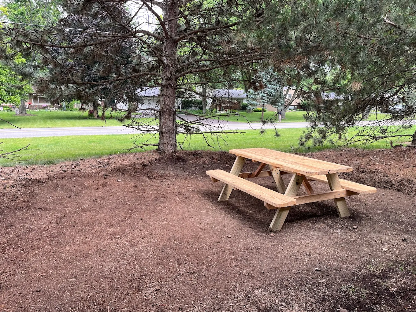 Wooden picnic table under trees outside facility