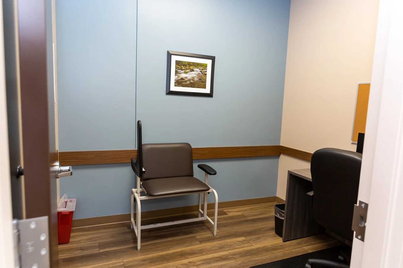 BrightView Danville exam room with medical chair, staff workstation, blue accent wall, and framed nature artwork