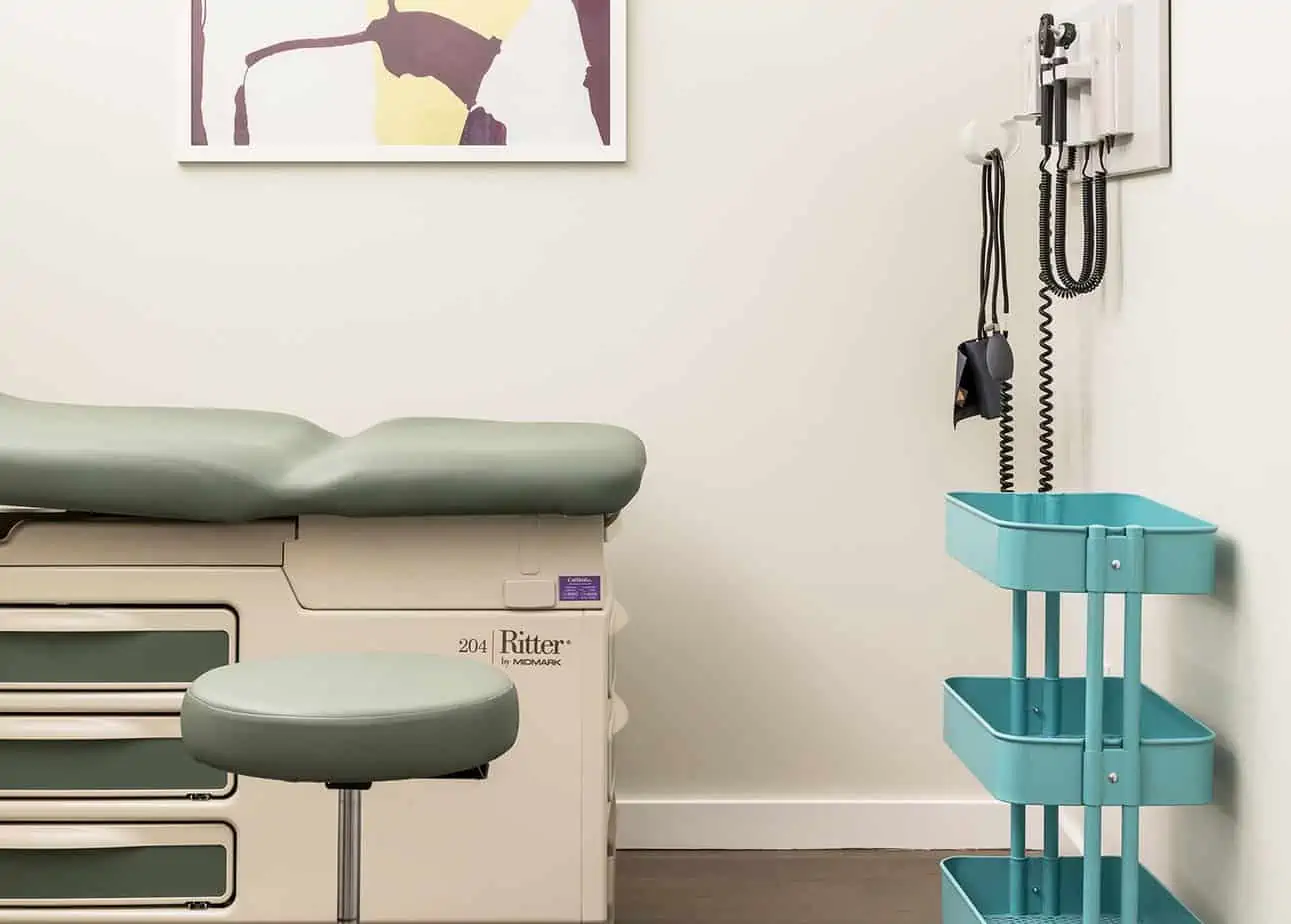 Exam table and stool with medical tools on wall