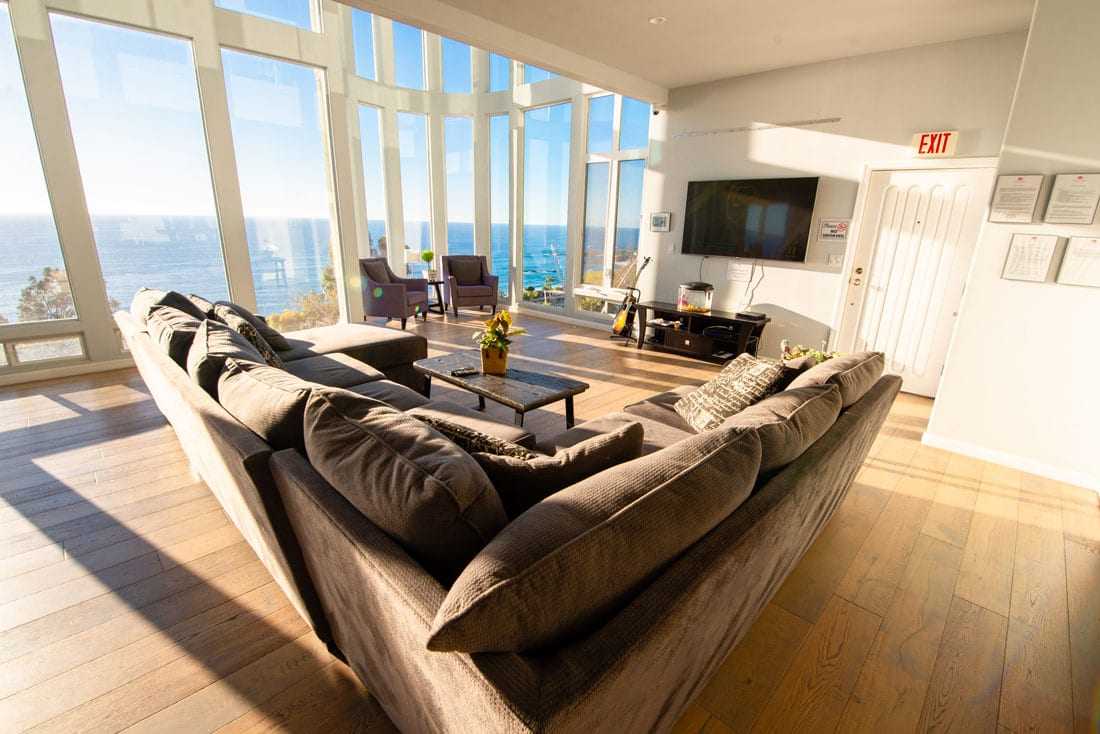 Sofa facing TV and large windows overlooking the sea