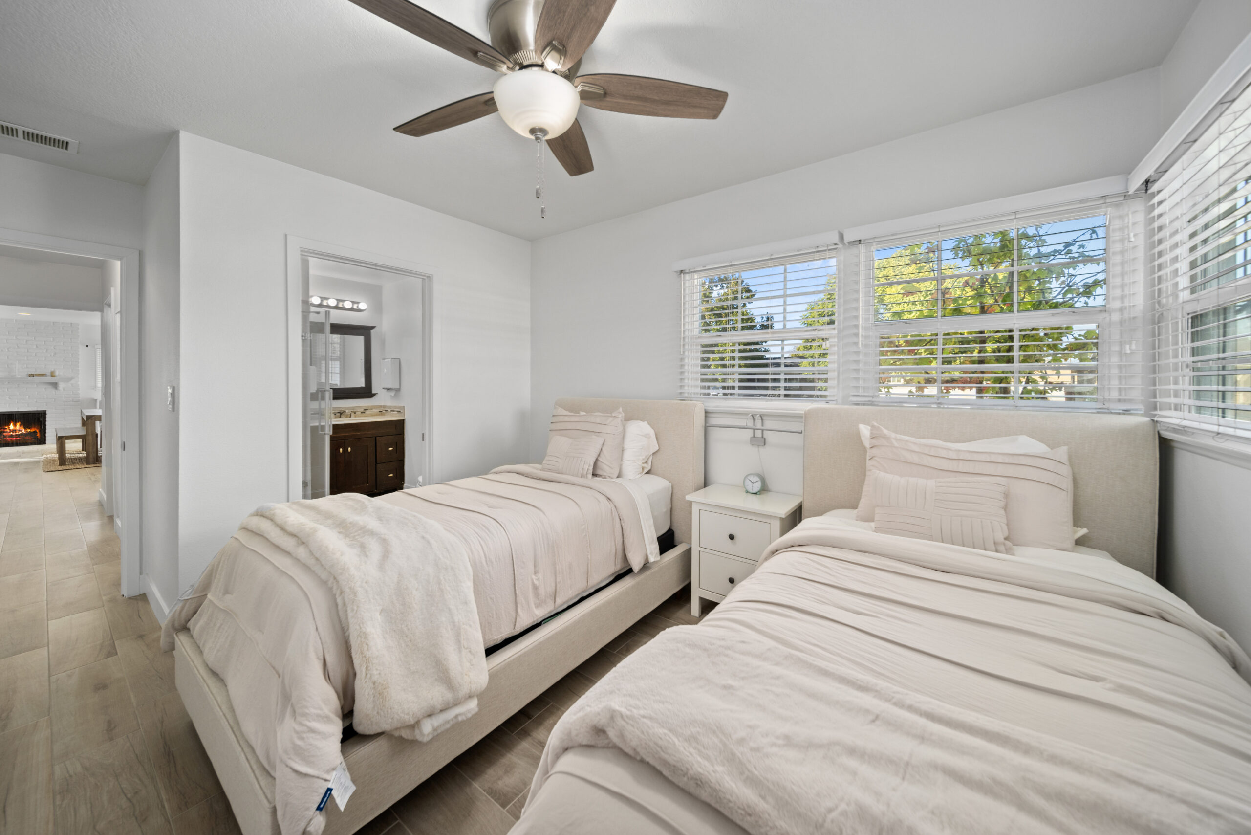Twin beds with white linens and view of connected bathroom