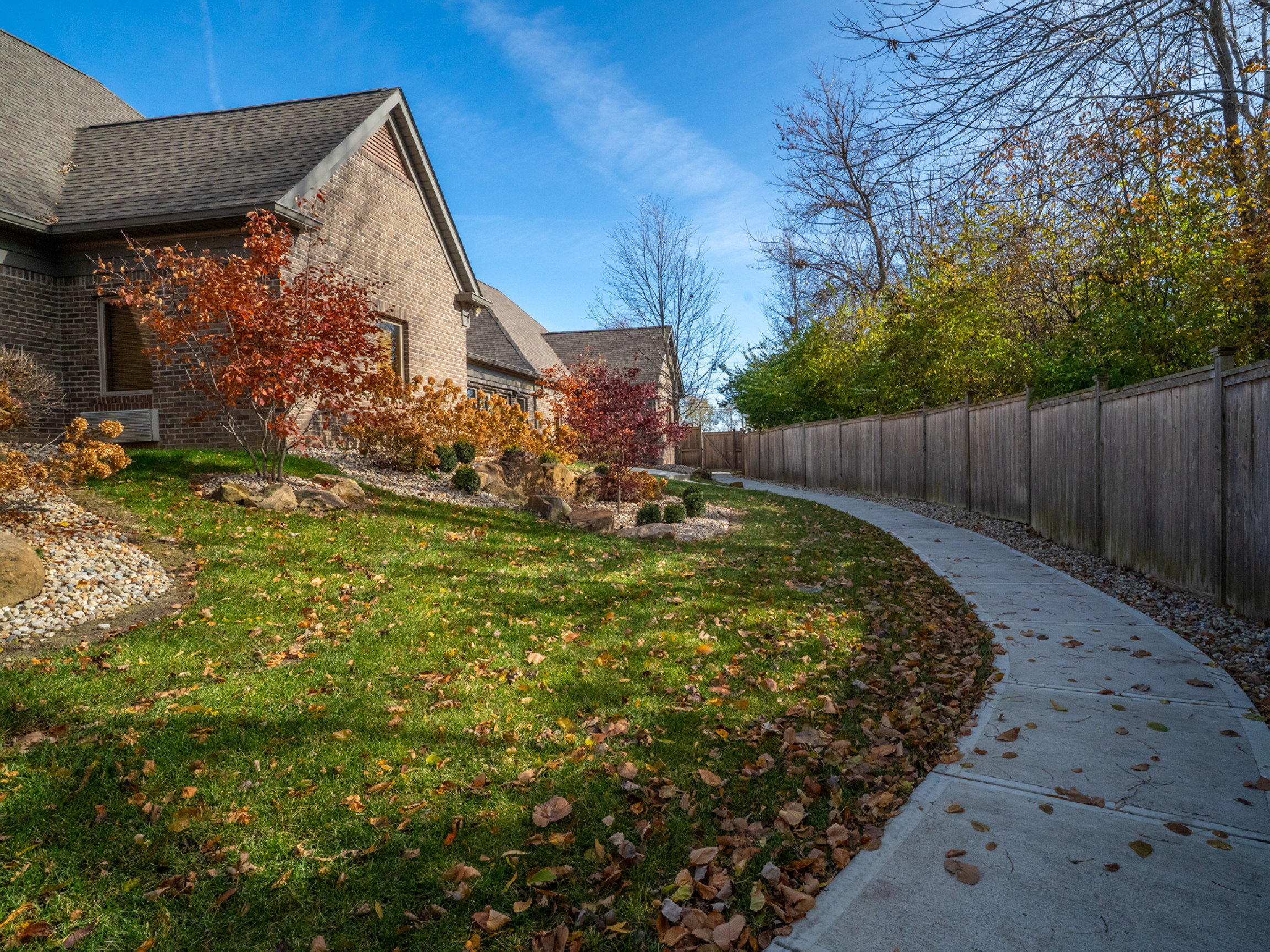 Paved path beside building with fall trees.