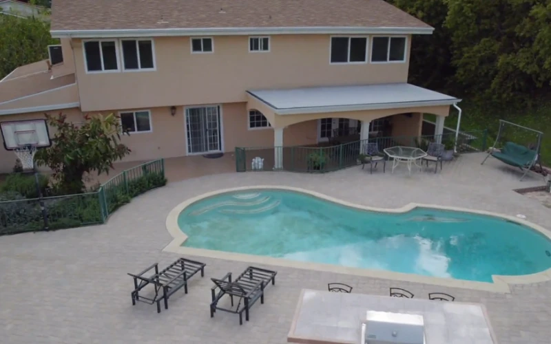 Curved swimming pool with lounge chairs and patio