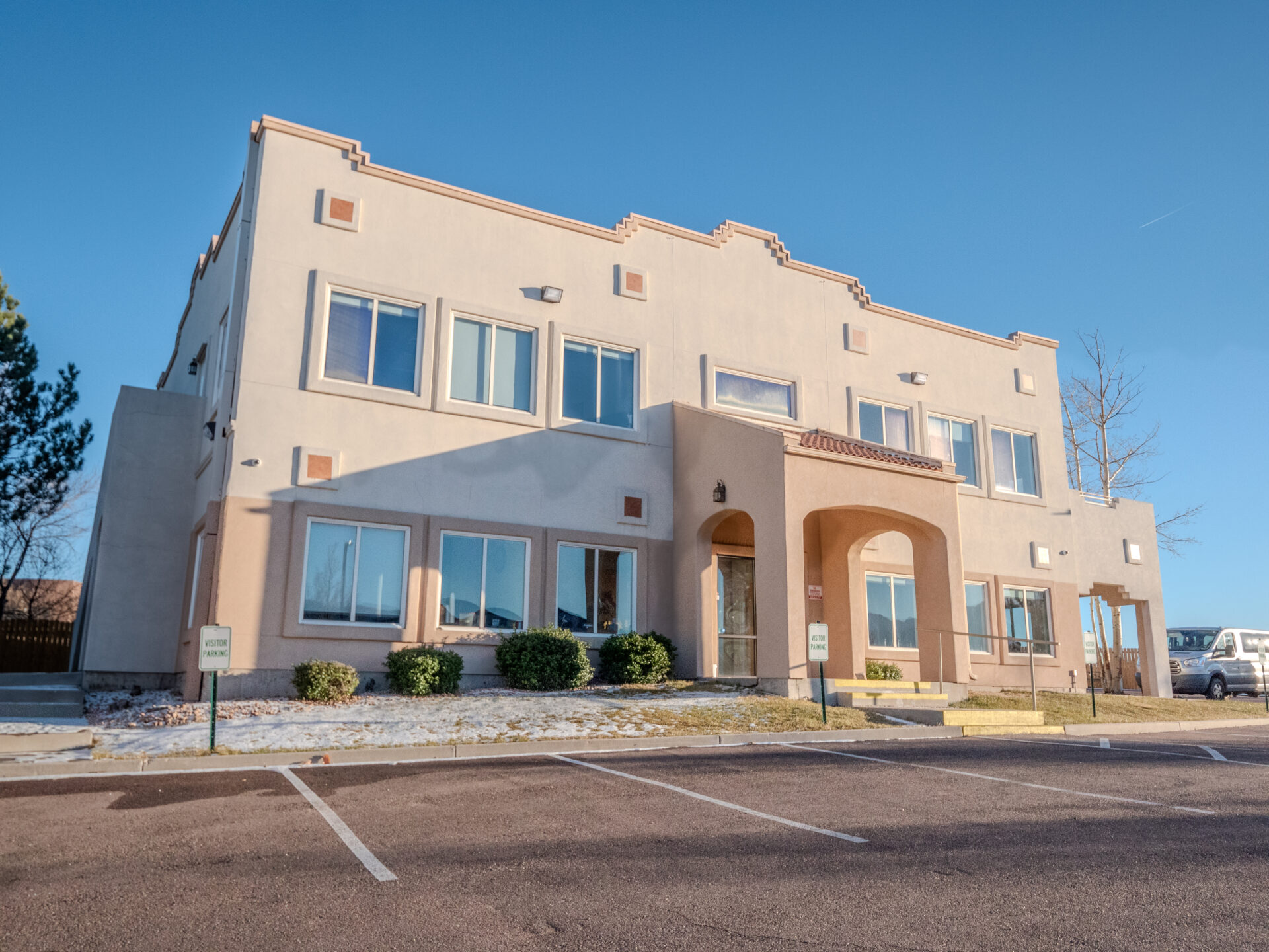 Modern tan two-story facility with arched entrance and windows