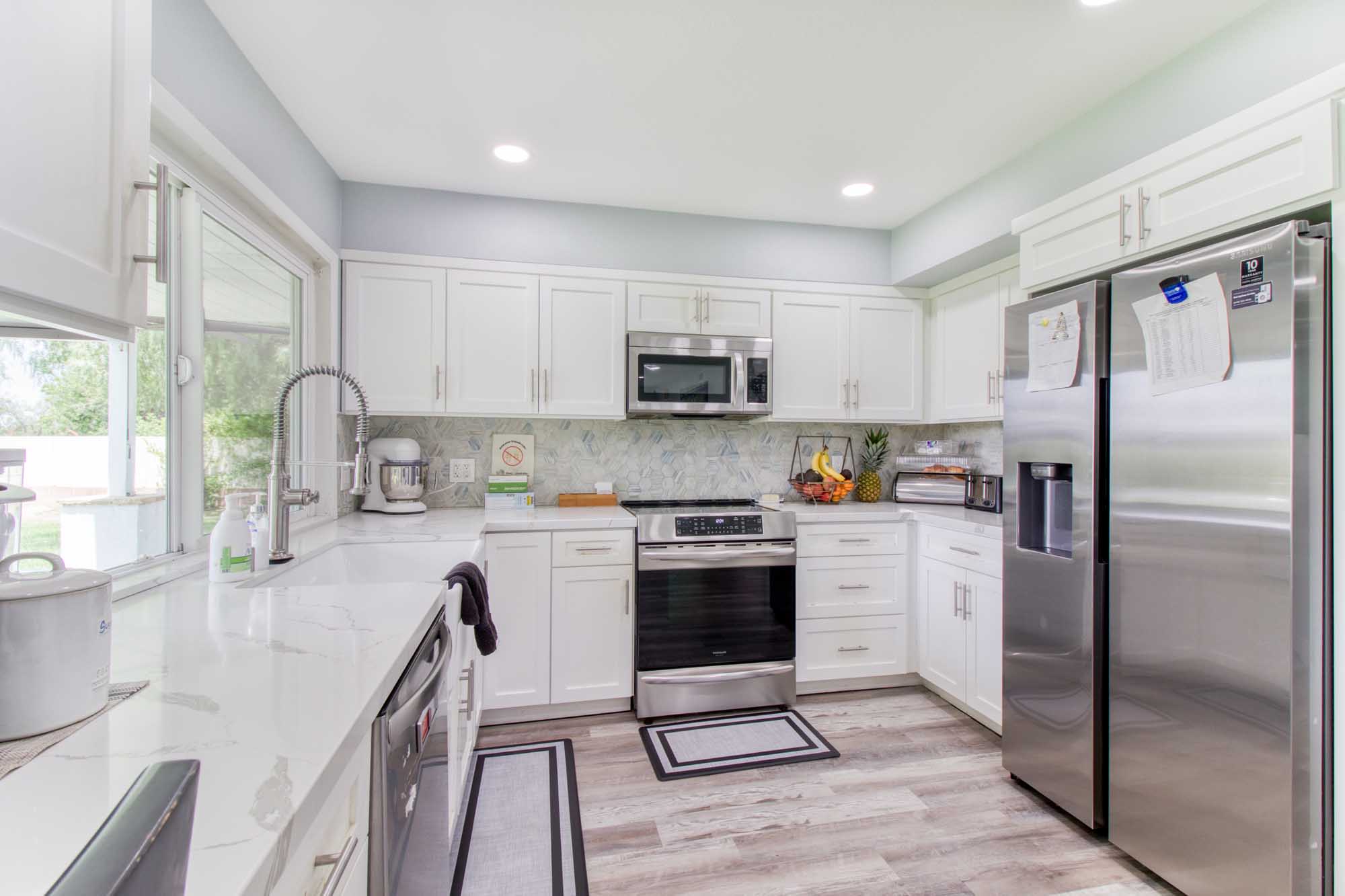 Kitchen with white cabinets, tile backsplash, and stainless appliances