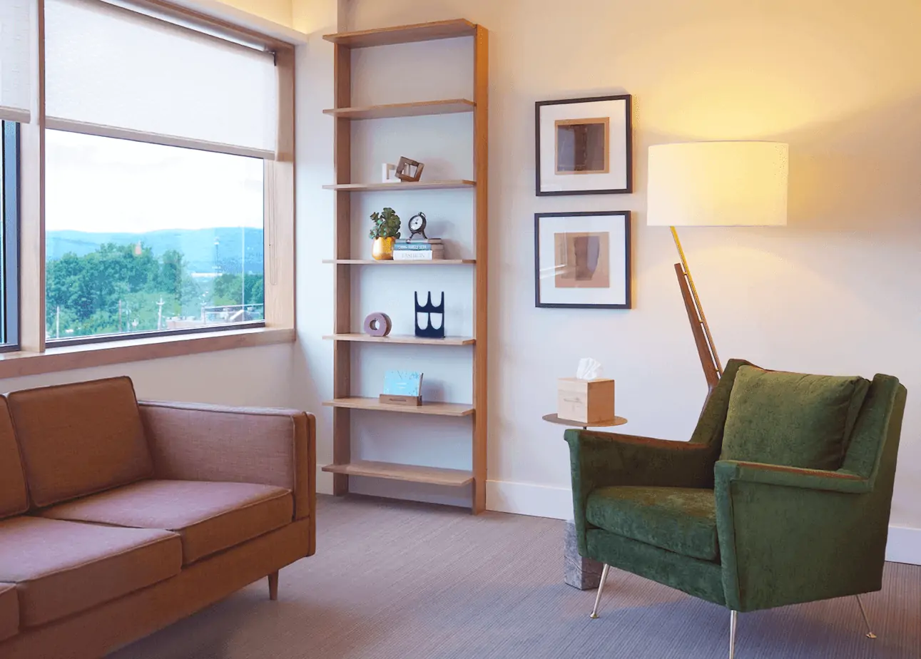 Green armchair and sofa beside wall shelves and window