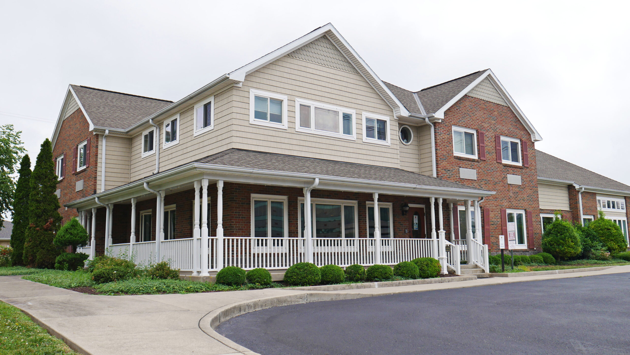 Two-story residential facility with wraparound porch and landscaping.