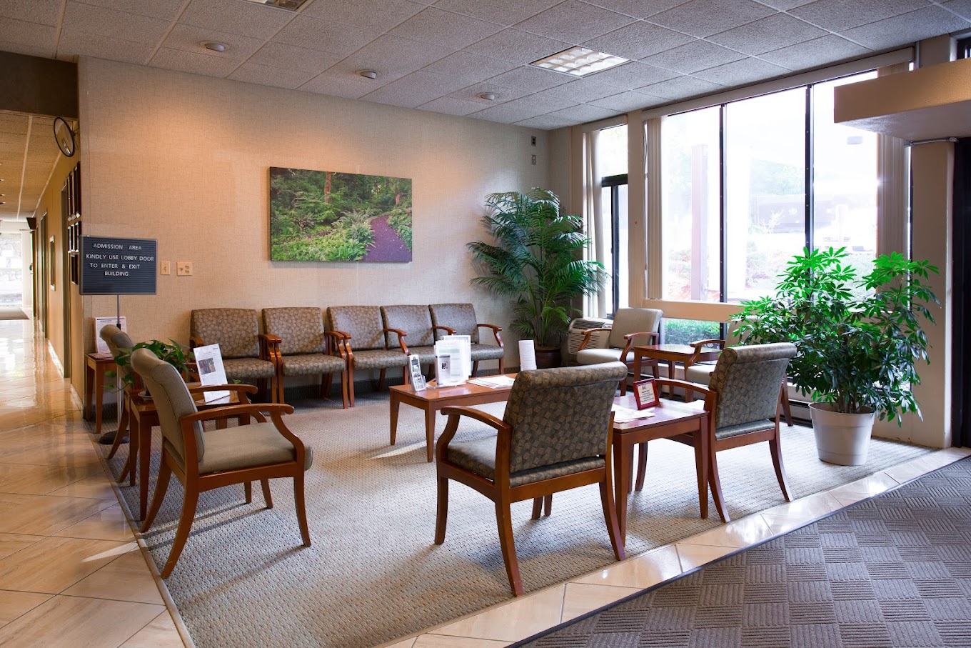 A spacious waiting area with chairs, tables, and large windows.