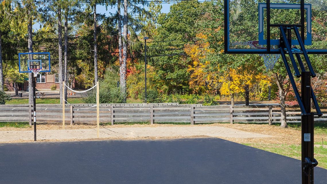Outdoor basketball court with nearby sand volleyball net