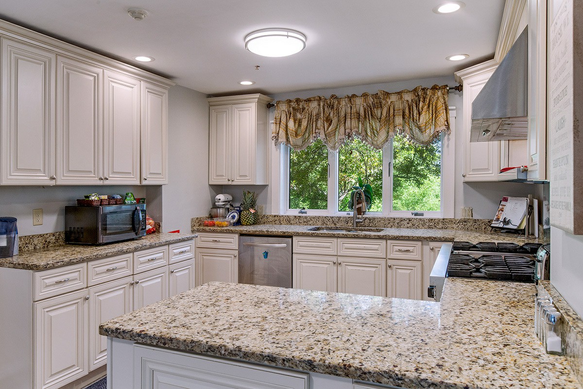 Spacious kitchen with granite counters and white cabinets