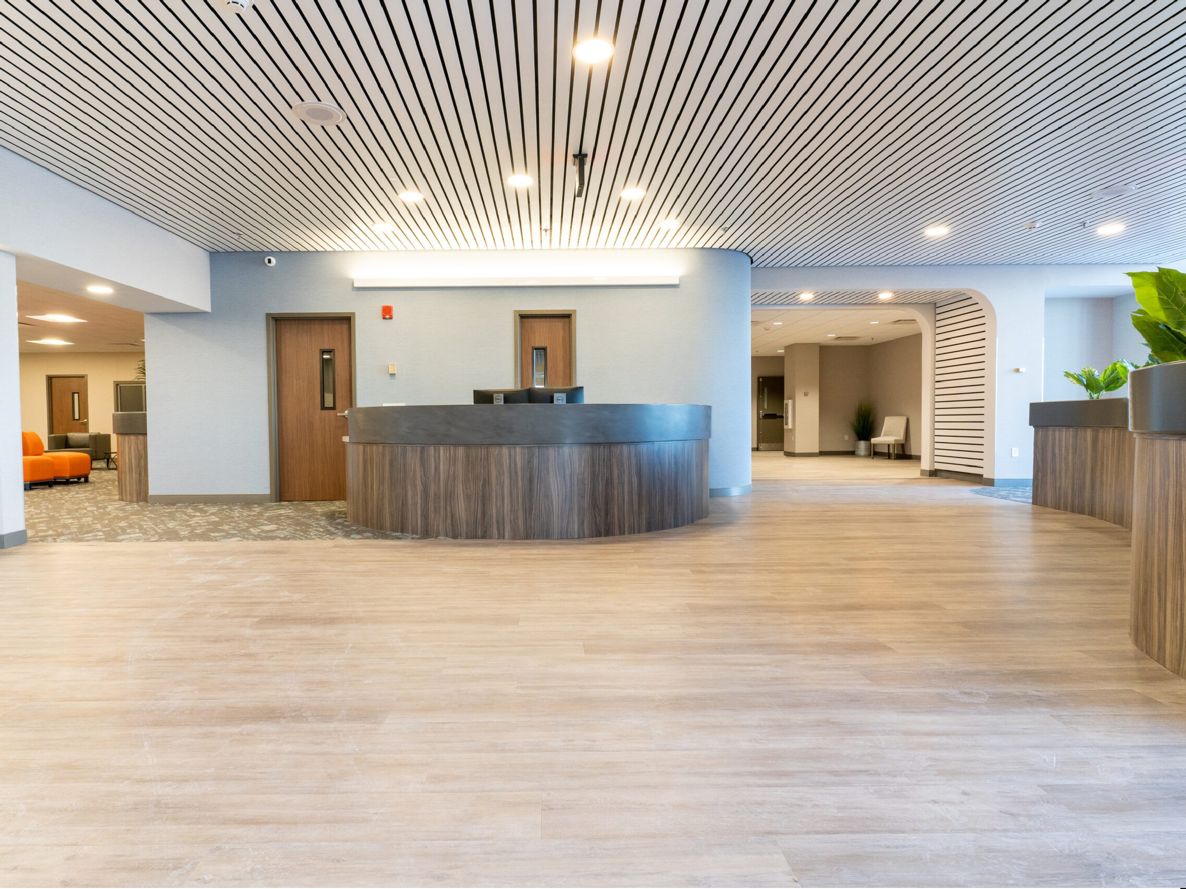 Spacious modern lobby with curved desk and wood flooring.
