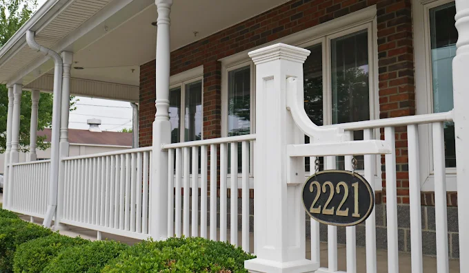 Brick porch with white railing and address sign