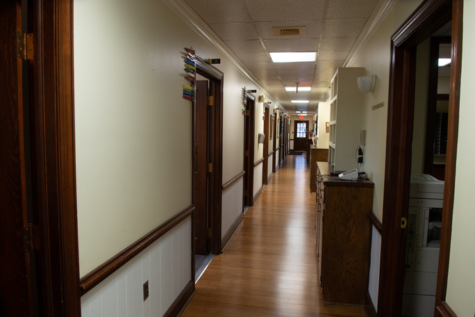 Clean hallway with wood floors and multiple office doors