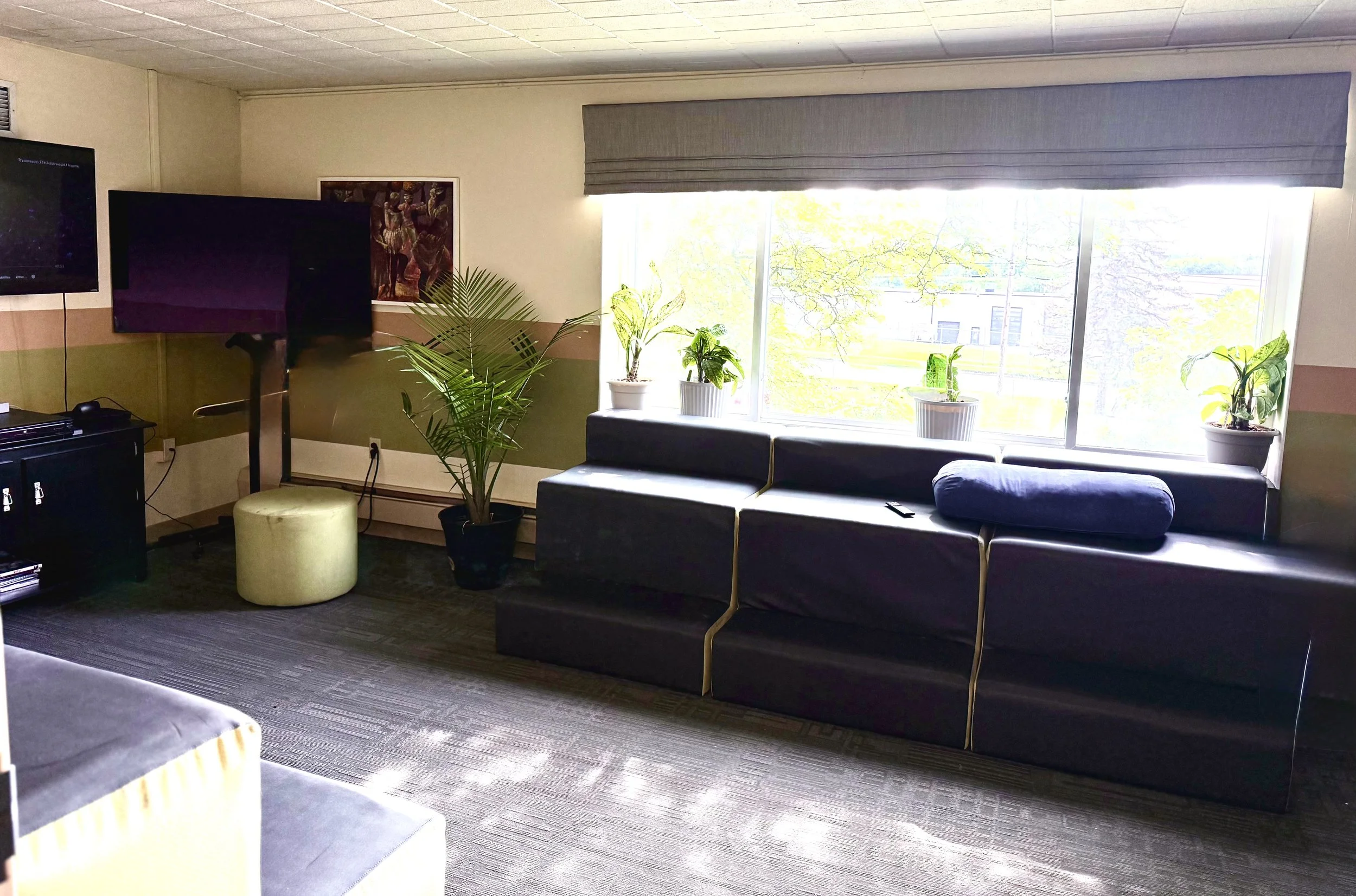 Common room with couches, TV screens, and natural light