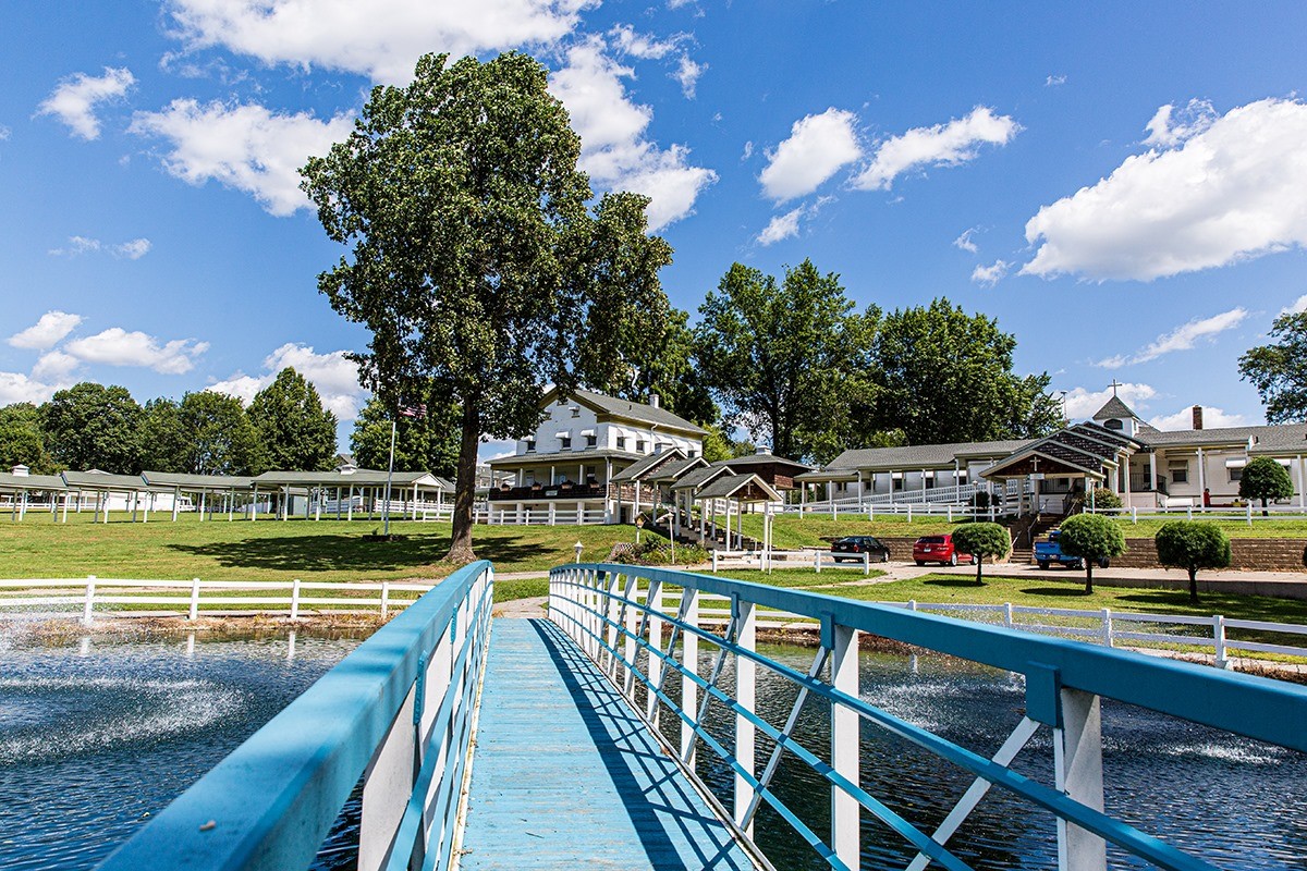 Blue footbridge over pond leading to recovery campus buildings