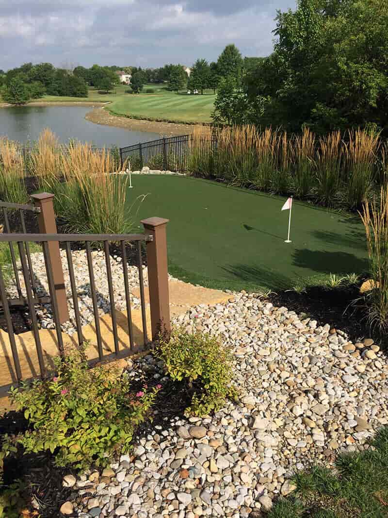 Mini putting green beside a lake with landscaping