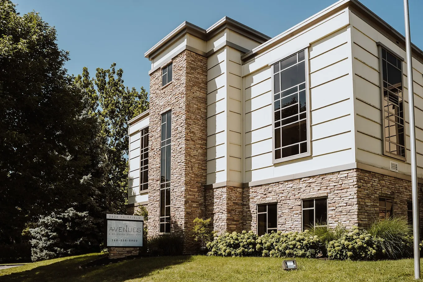 Rehab facility entrance with trees and stone facade