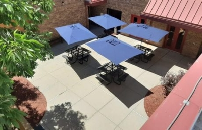 Outdoor patio with picnic tables and blue umbrellas