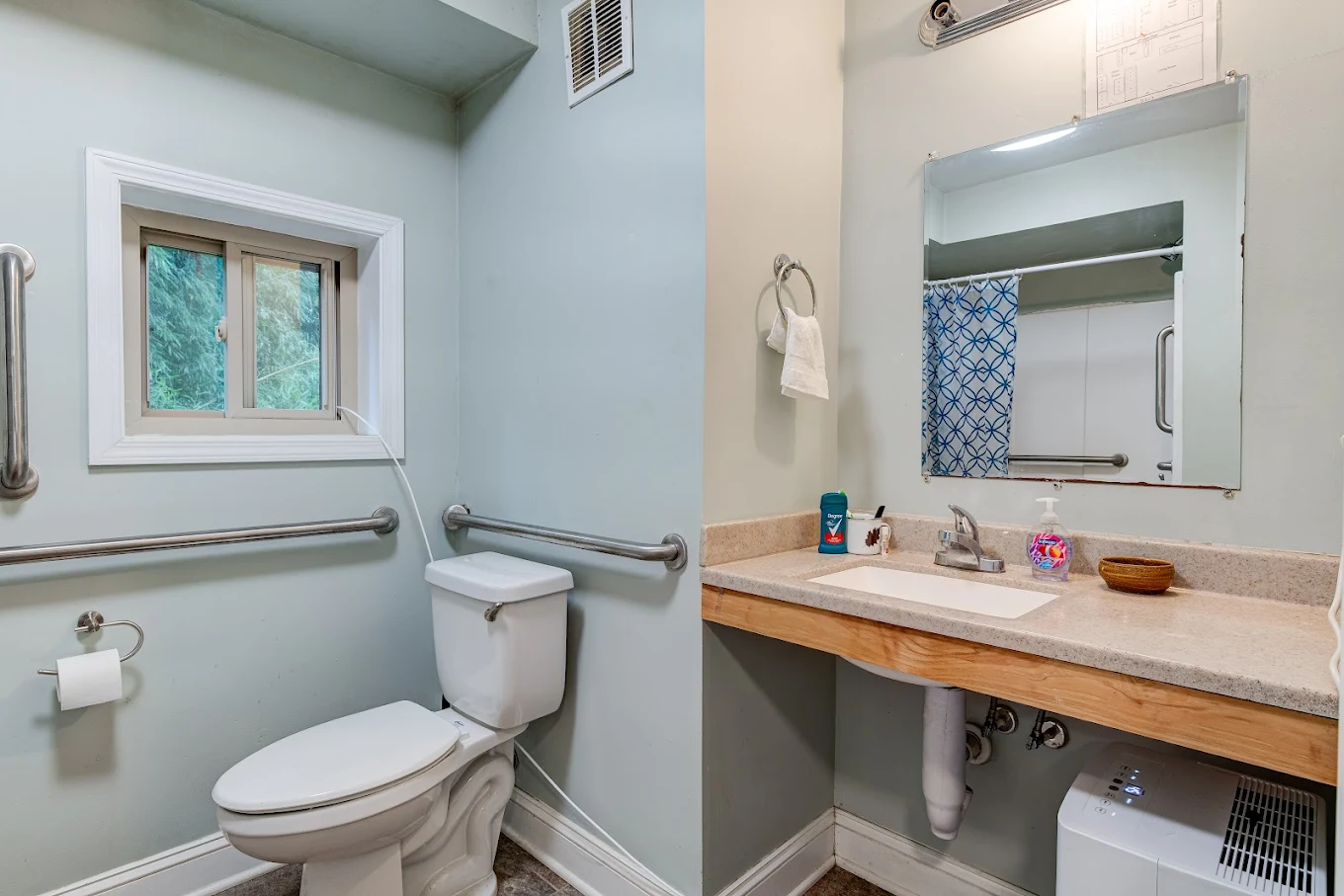 Accessible bathroom with sink, mirror, and grab bars