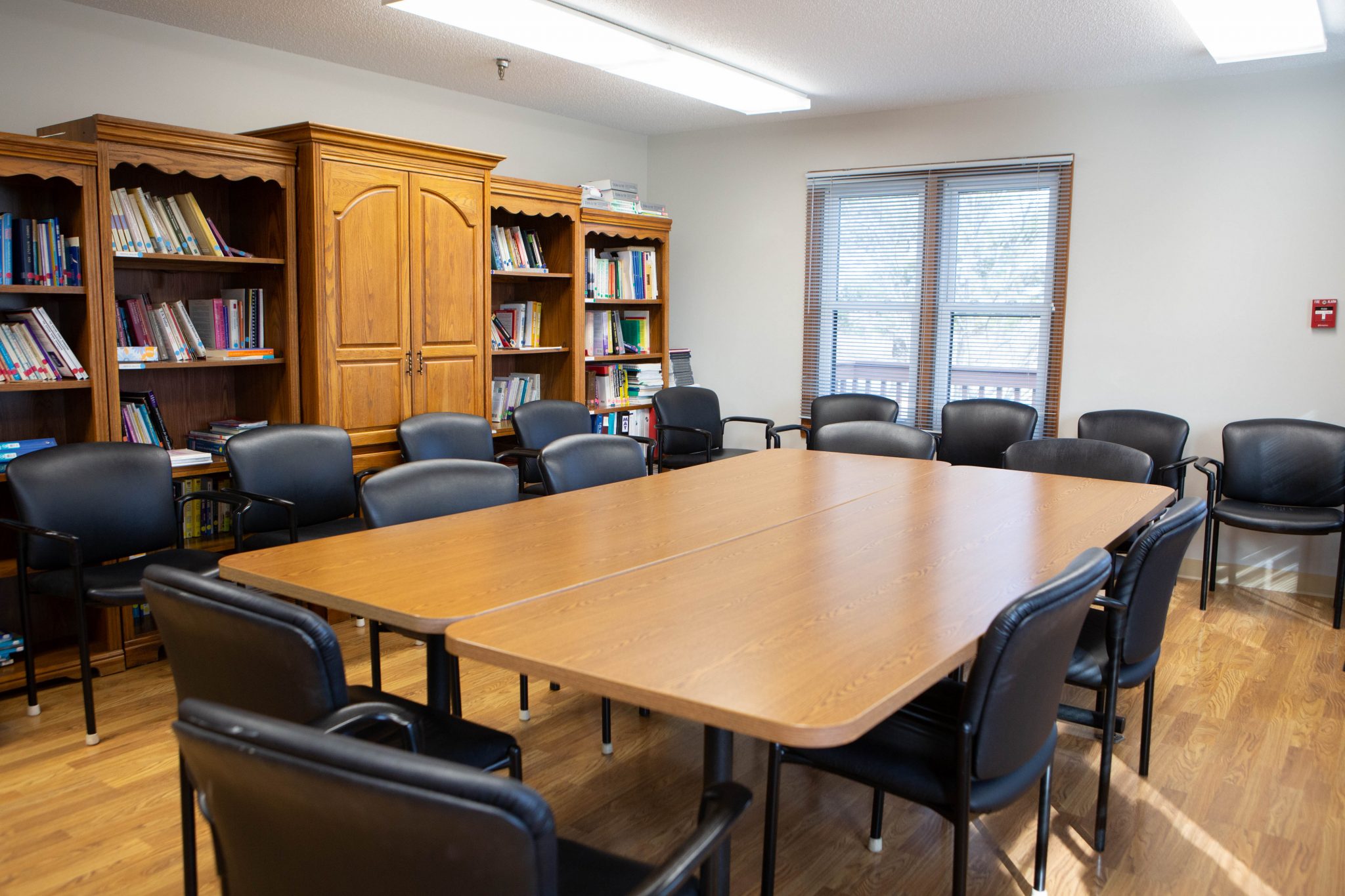 Meeting room with bookshelves, conference tables, and rows of black chairs.