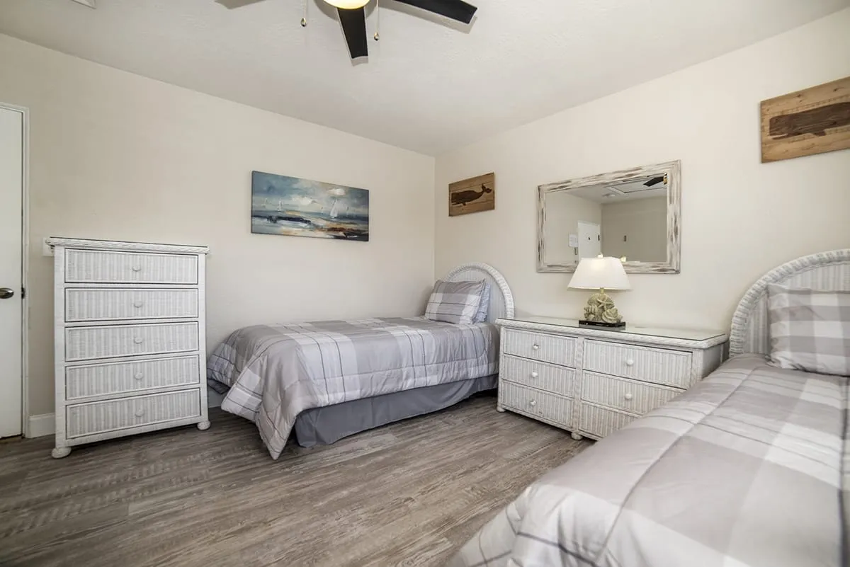 Twin beds with gray bedding and wicker dressers