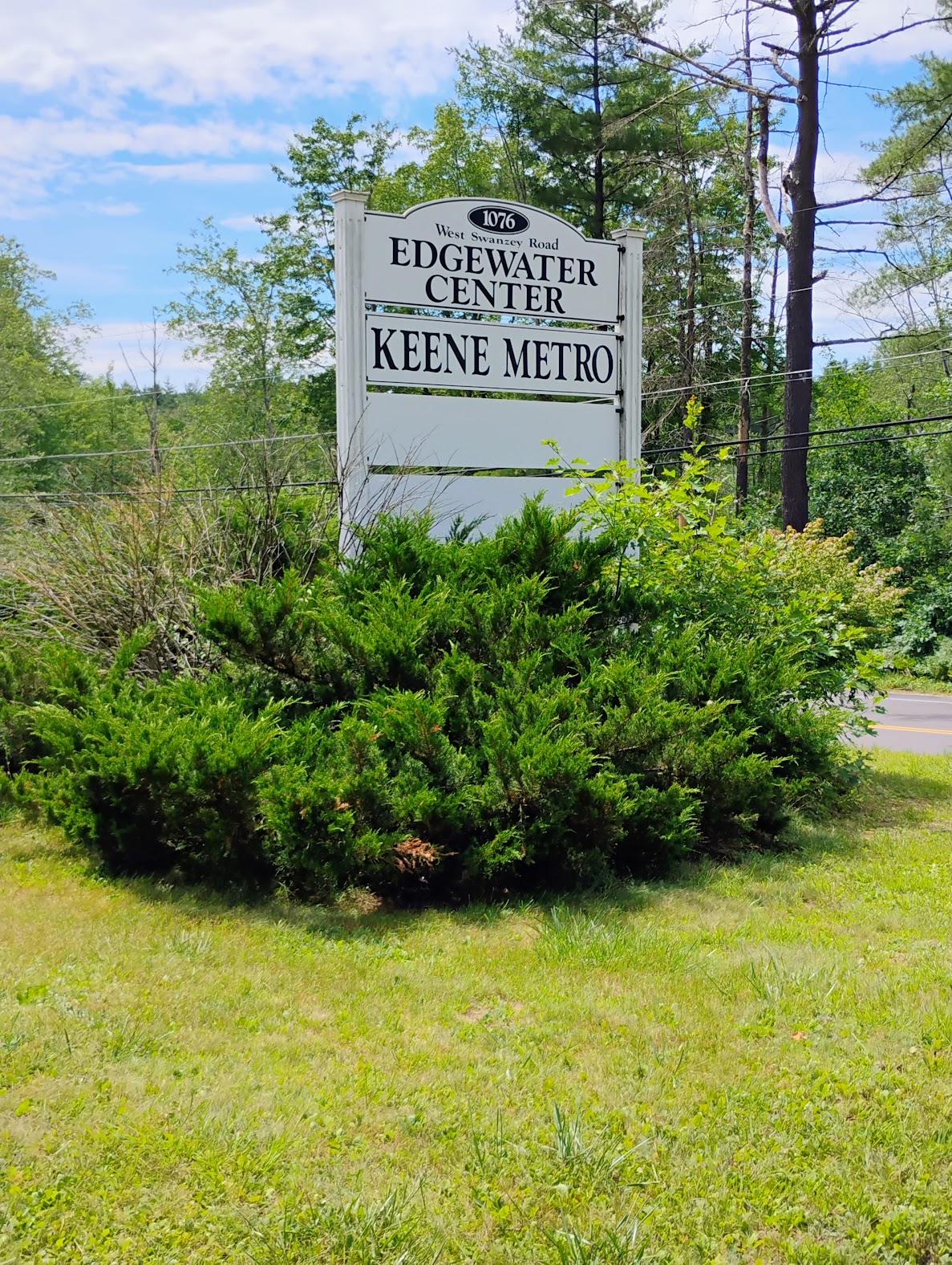 Keene Metro sign with shrubs and trees in background
