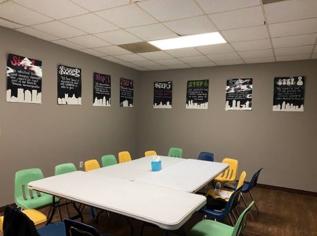 Group therapy room with meeting table and recovery posters