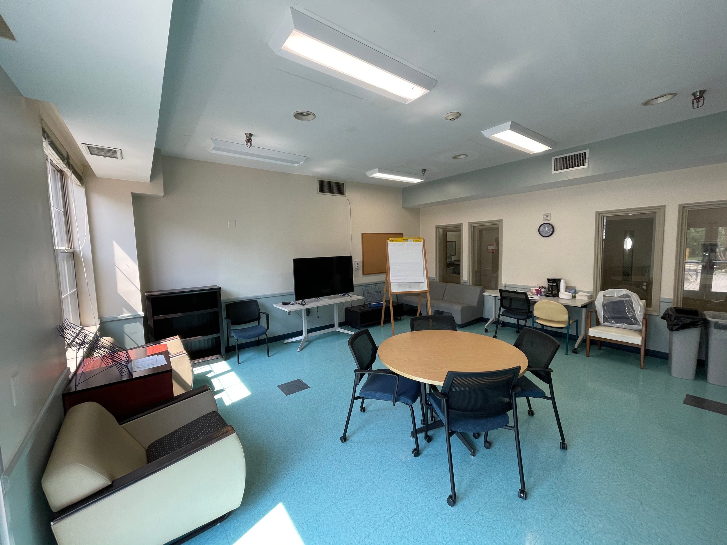 Group meeting room with chairs, round table, and TV setup