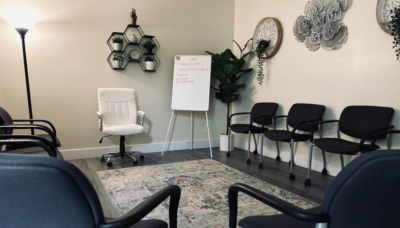 Group therapy room with chairs, a whiteboard, and decor.
