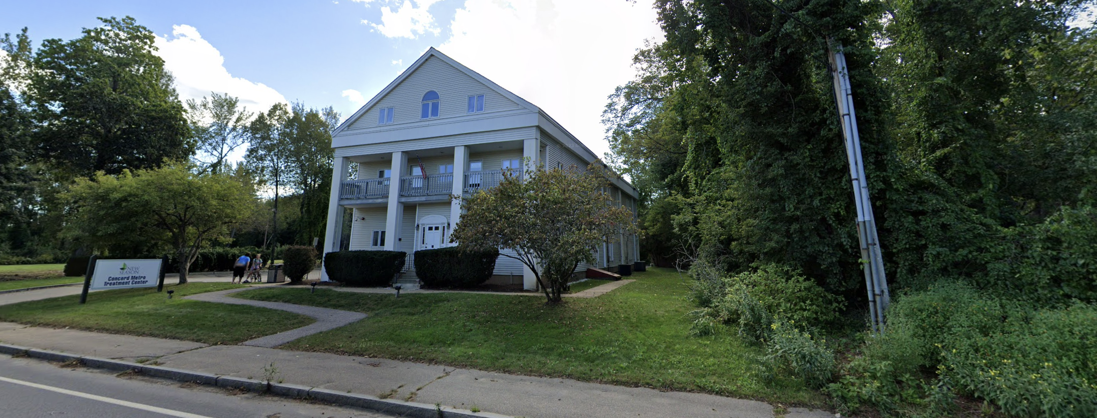 A large white building with columns, surrounded by greenery and trees.