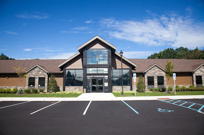 Modern rehab center entrance with peaked roof and parking