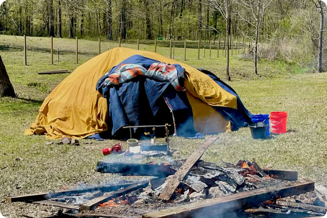 Covered sweat lodge near open campfire