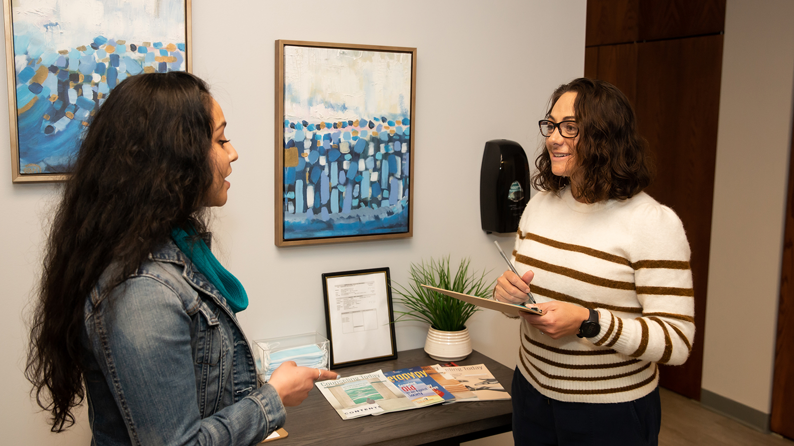 Two people talking near brochures in a lobby.