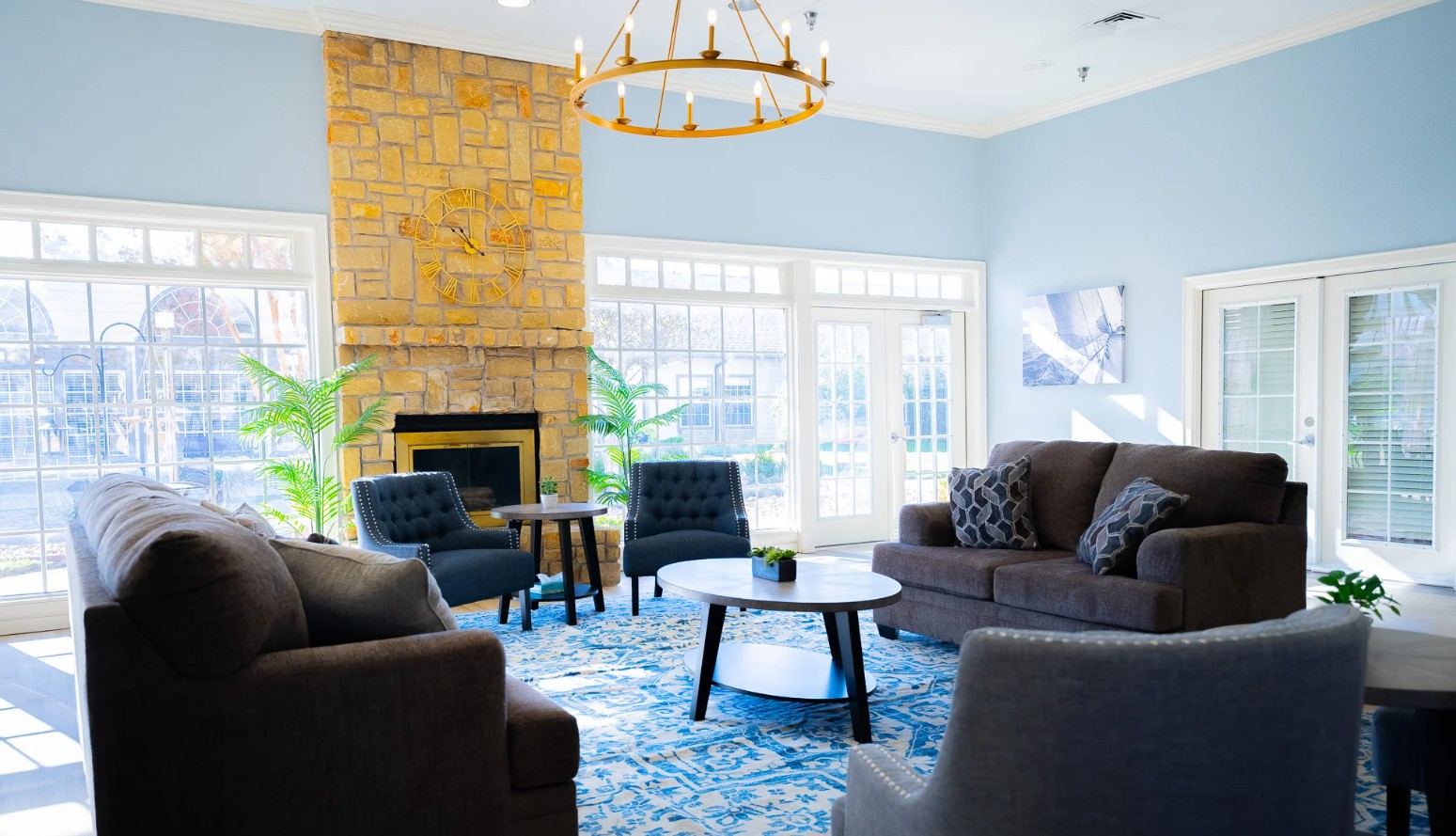 Bright community lounge featuring a stone fireplace, comfortable seating, and large windows at Promises Dallas–Fort Worth