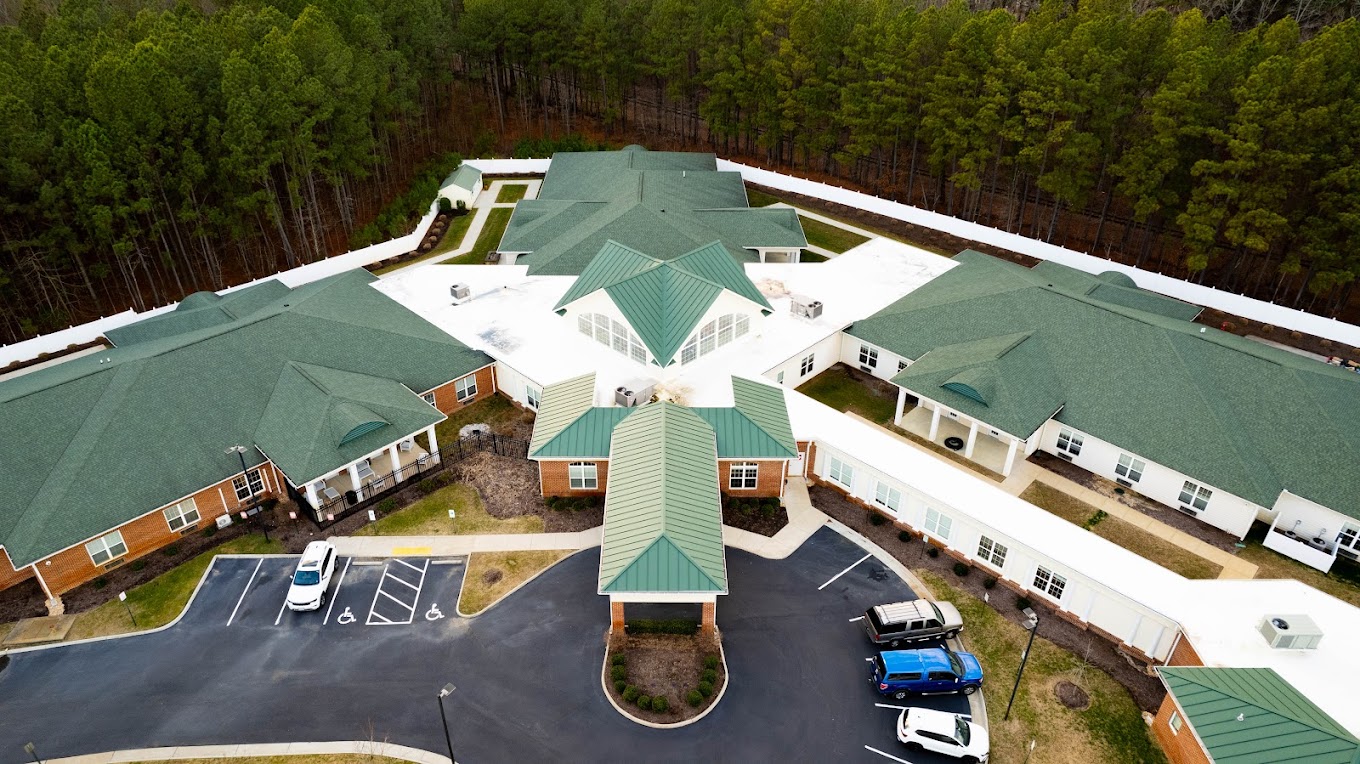 Aerial view of a rehab facility with green roofs and surrounding trees.